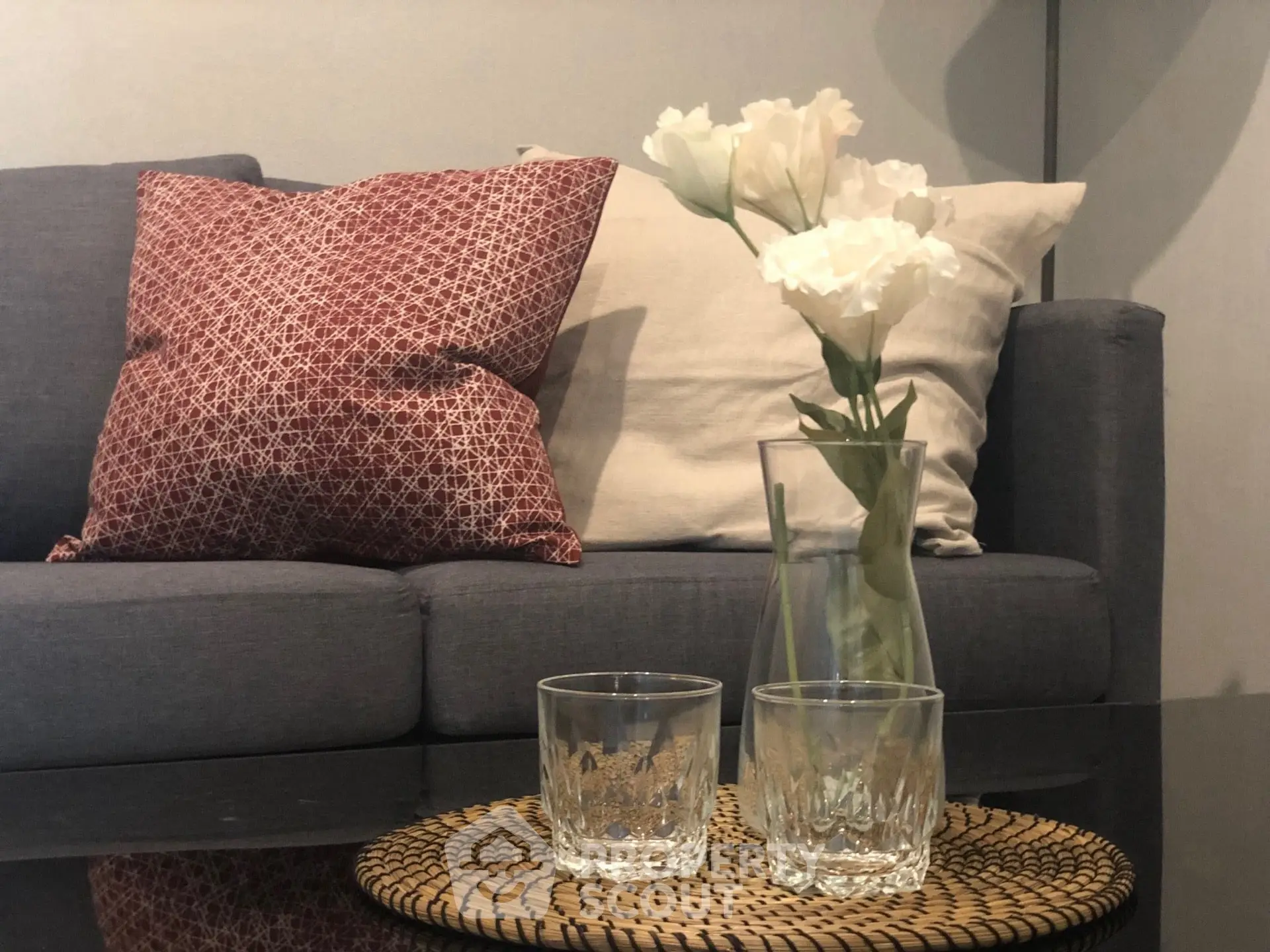 Stylish living room with cozy sofa, decorative pillows, and elegant flower vase on coffee table.