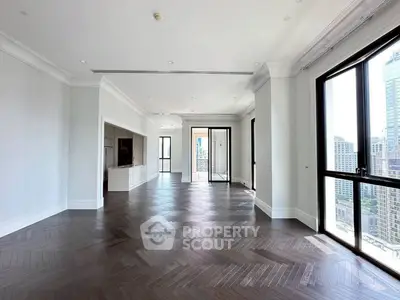 Spacious modern living room with large windows and city view, featuring elegant dark wood flooring.