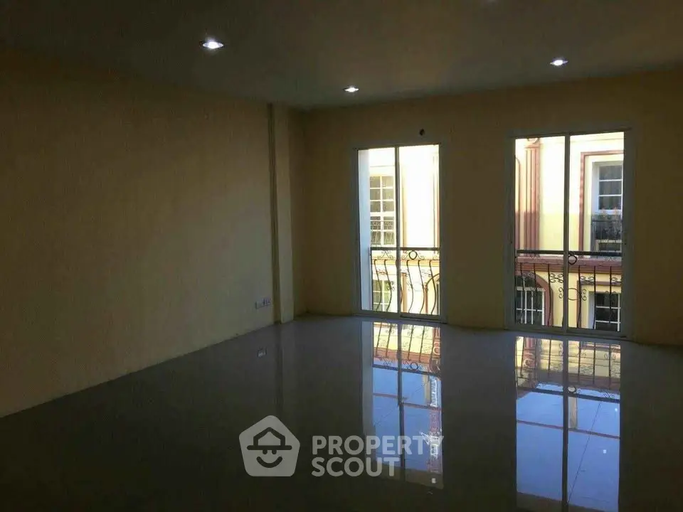 Spacious empty room with large windows and glossy floor reflecting natural light.