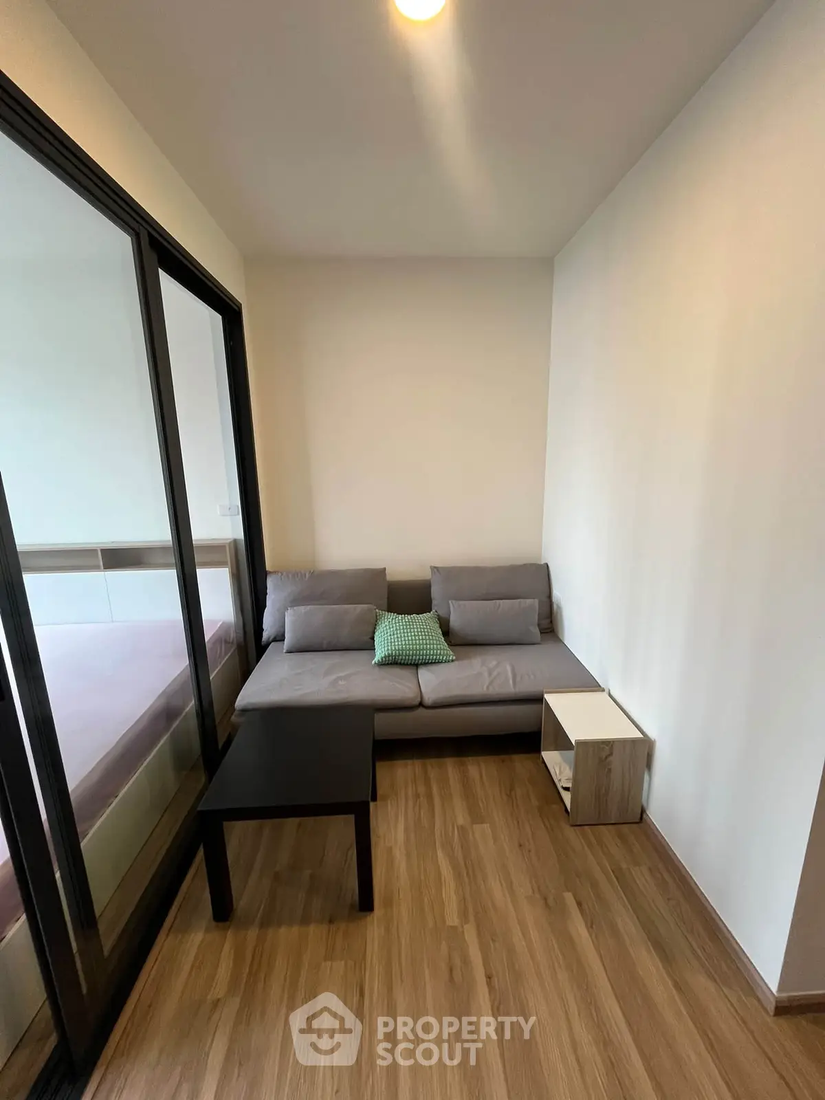 Cozy living room with modern furniture and wooden flooring in a compact apartment.