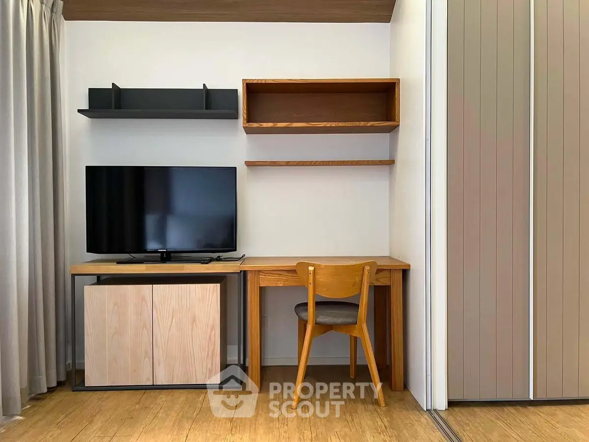 Modern study area with wooden desk, chair, and TV in a stylish apartment.