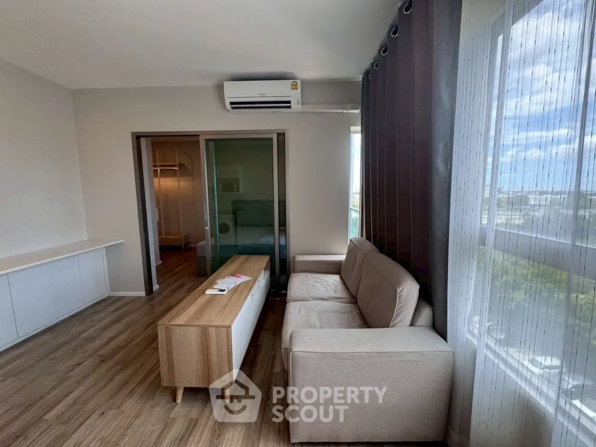 Modern living room with large window and cozy sofa in a bright apartment.
