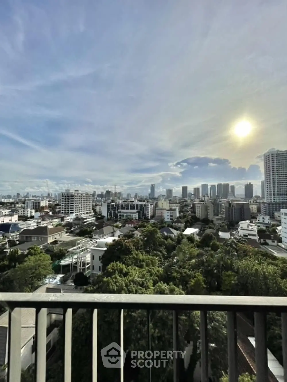 Stunning cityscape view from a high-rise balcony showcasing urban skyline and lush greenery.