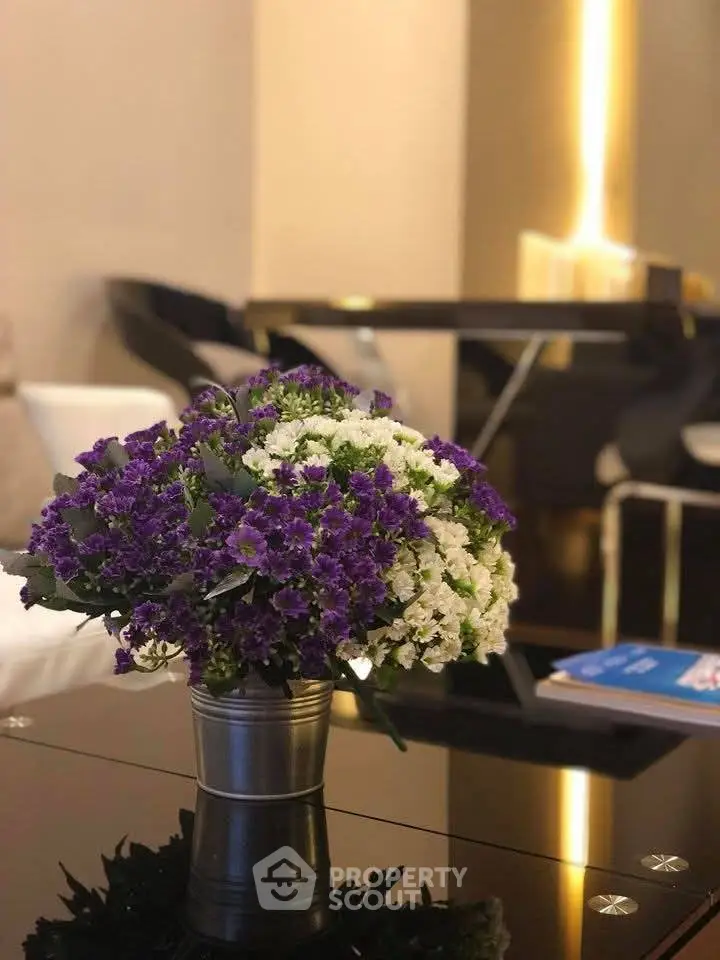 Elegant living room with modern decor and vibrant floral centerpiece on glass table.