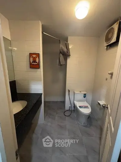 Modern bathroom with sleek fixtures and tiled walls, featuring a stylish vanity and contemporary toilet.