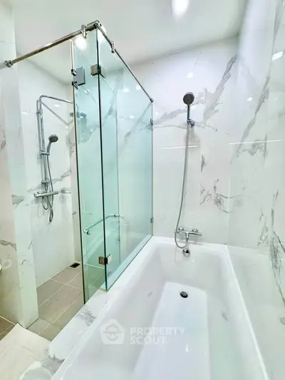 Luxurious modern bathroom with marble tiles and glass shower enclosure