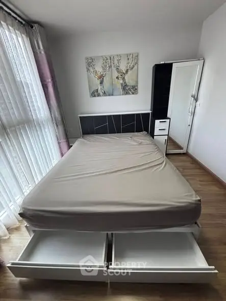 Spacious bedroom with modern bed and ample natural light from large window.