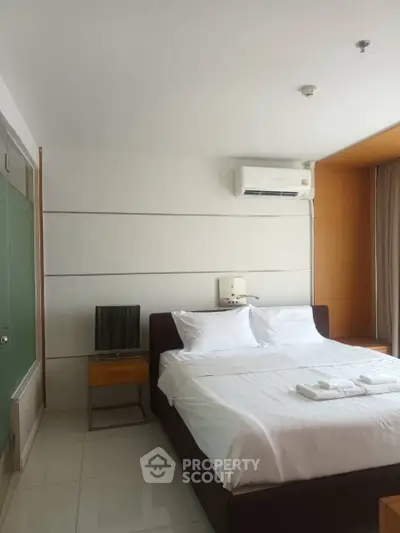 Modern bedroom with sleek design, featuring a comfortable bed, air conditioning, and minimalist decor.