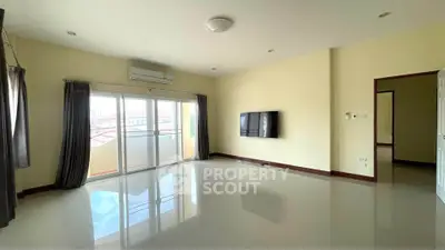 Spacious living room with large windows and wall-mounted TV, perfect for modern living.