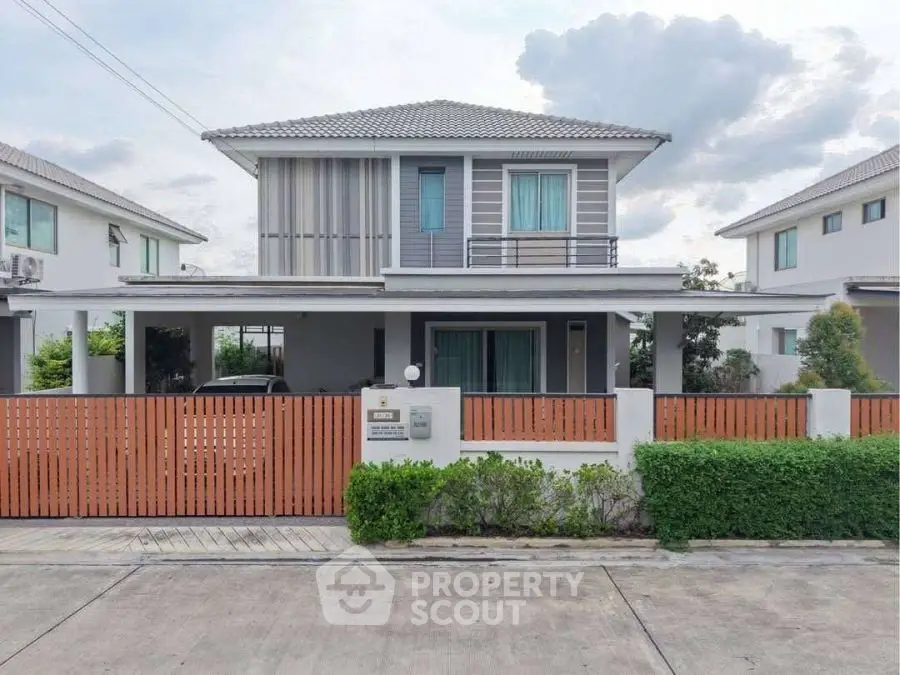 Modern two-story house with stylish facade and gated entrance in suburban neighborhood.