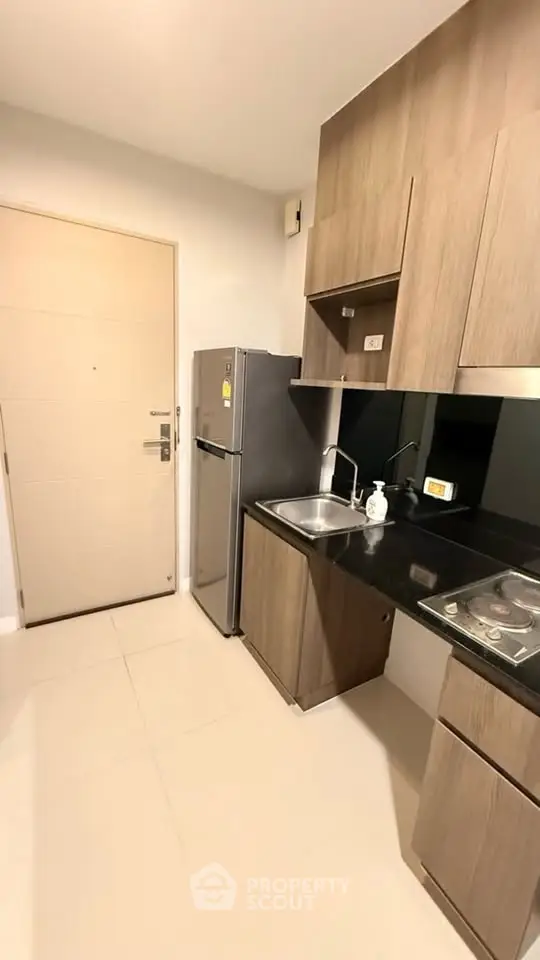 Modern compact kitchen with sleek cabinetry and stainless steel appliances in a stylish apartment.