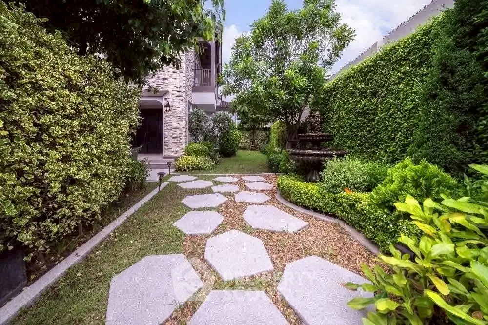 Charming garden pathway leading to a modern home with lush greenery and stone accents.