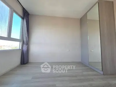 Spacious empty room with large window and mirrored wardrobe, perfect for customization.