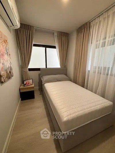 Cozy bedroom with single bed and elegant curtains, perfect for a serene retreat.