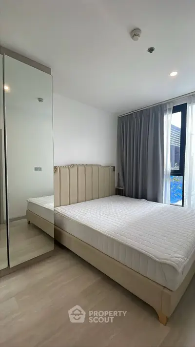 Modern bedroom with large mirror and elegant bed in a bright apartment.