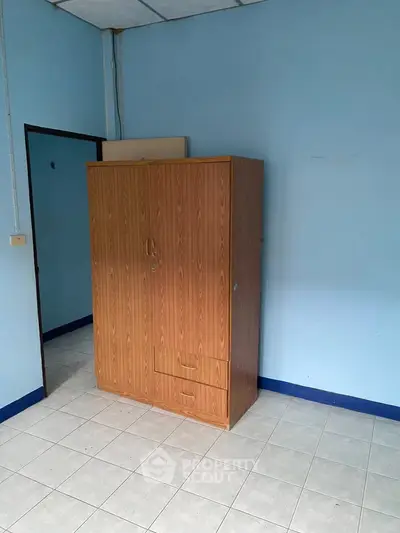 Spacious room with wooden wardrobe and tiled flooring, perfect for storage solutions.
