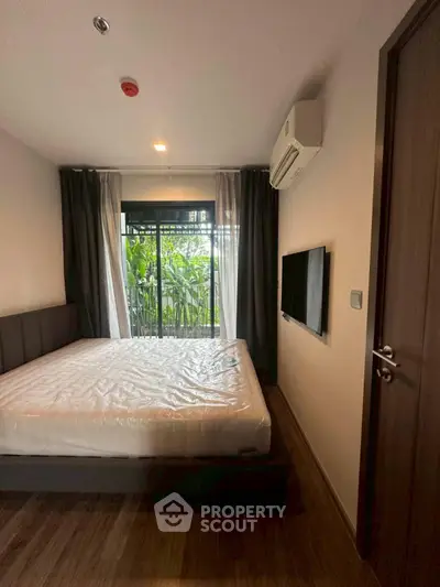 Cozy bedroom with balcony view and modern amenities in a stylish apartment.