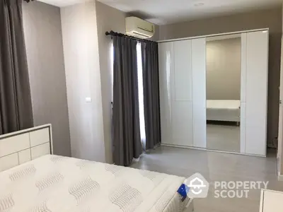 Spacious and modern bedroom with large mirrored wardrobe and elegant neutral tones, featuring air conditioning and ample natural light.