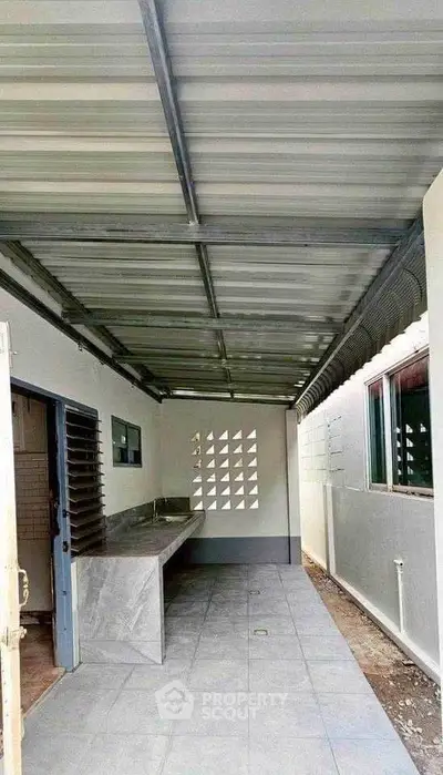 Spacious covered outdoor area with modern sink and tiled flooring, perfect for versatile use.