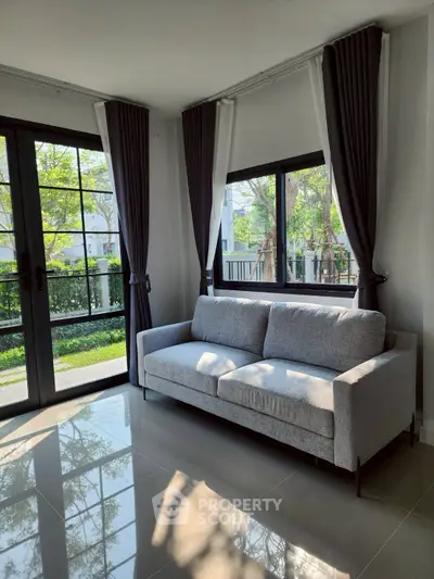Bright living room with large windows and modern gray sofa