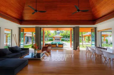 Luxurious open-plan living room with wooden ceiling and garden view, perfect for entertaining.