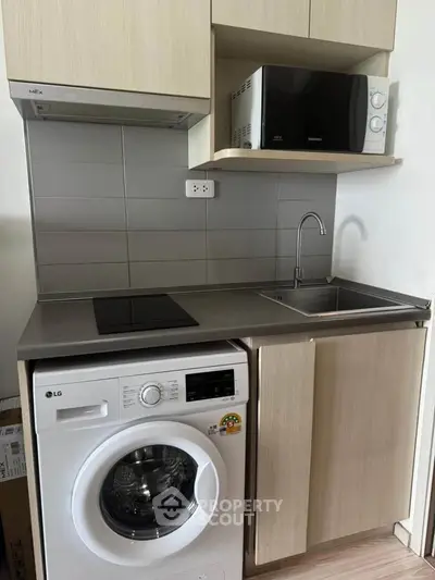 Compact kitchen with modern appliances including washing machine and microwave, ideal for urban living.