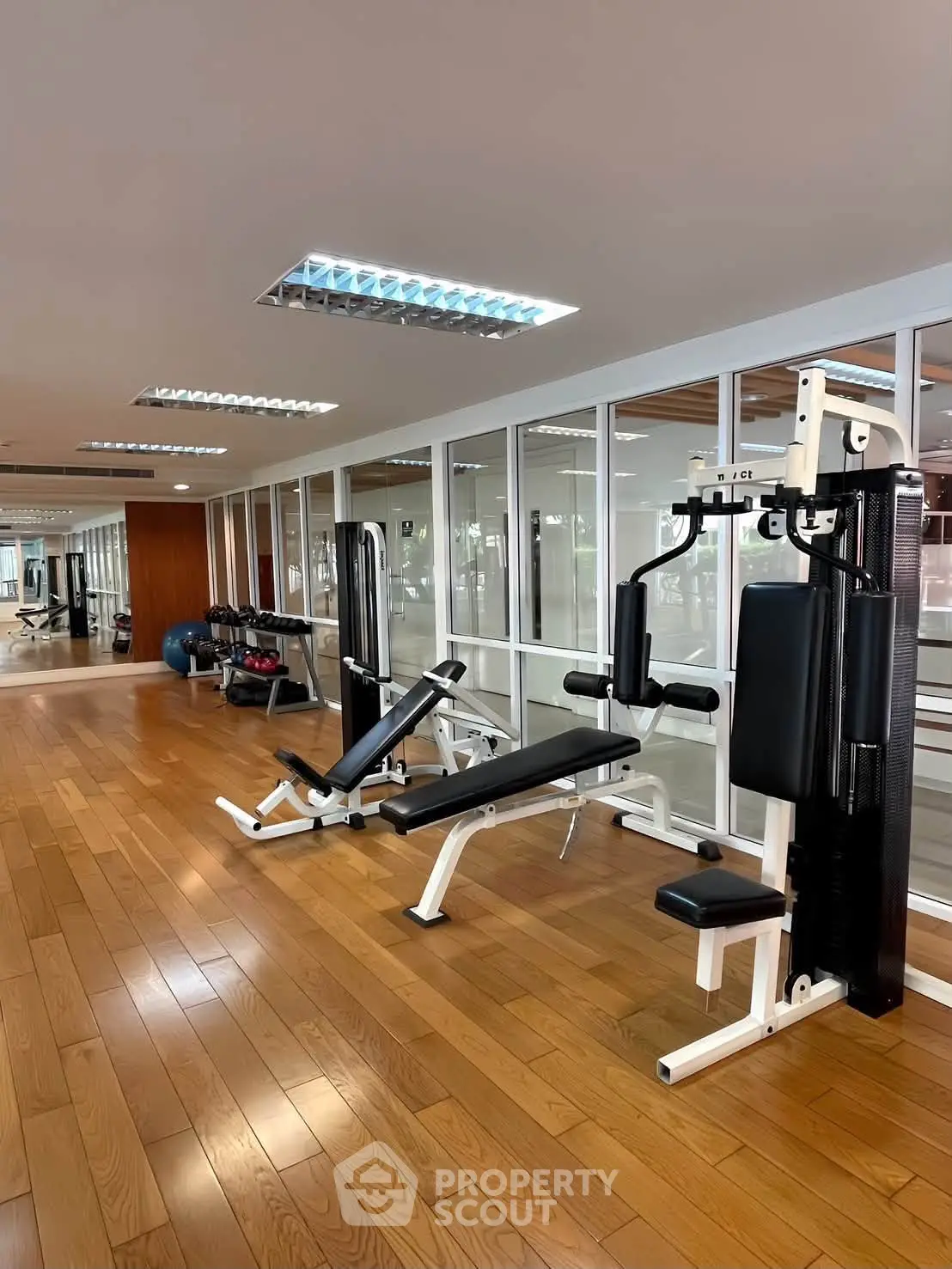 Spacious modern gym with state-of-the-art fitness equipment and wooden flooring in a luxury building.