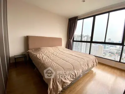 Spacious bedroom with large windows offering stunning city views in modern apartment.