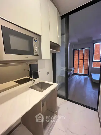 Modern kitchen with sleek design and integrated microwave in a stylish apartment.