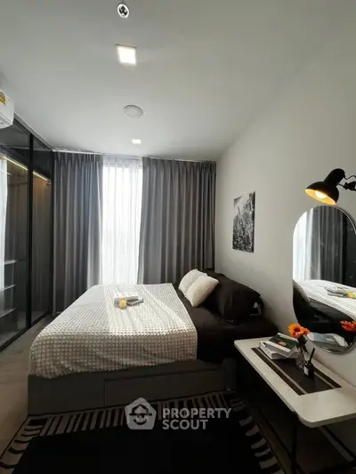 Modern bedroom with stylish decor and large window, featuring a cozy bed and elegant furnishings.
