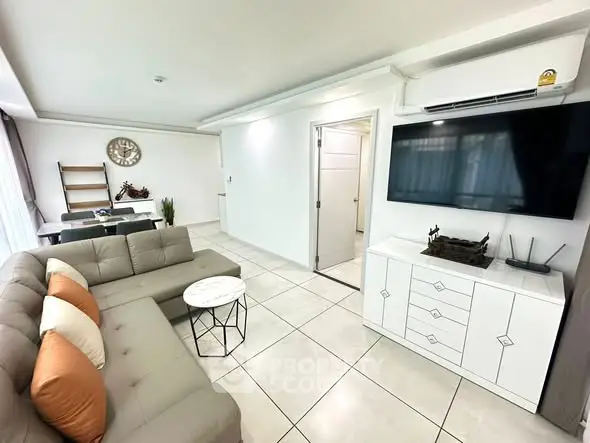 Modern living room with sleek furniture and wall-mounted TV in a bright, spacious setting.