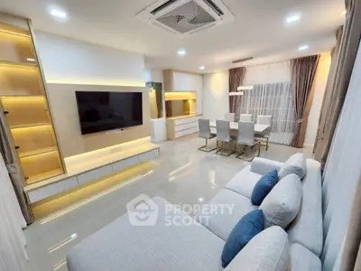Modern living room with sleek design, large TV, and elegant dining area.