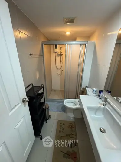 Compact bathroom with shower and modern fixtures in cozy apartment.