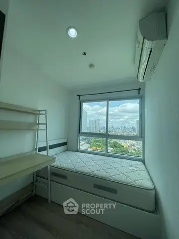 Compact bedroom with city view, featuring a single bed and air conditioning.