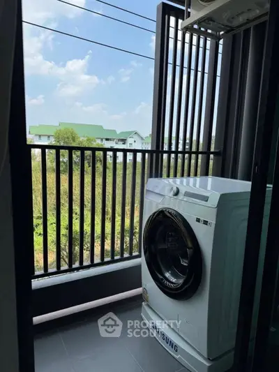 Modern balcony with washing machine and scenic view of greenery and buildings.