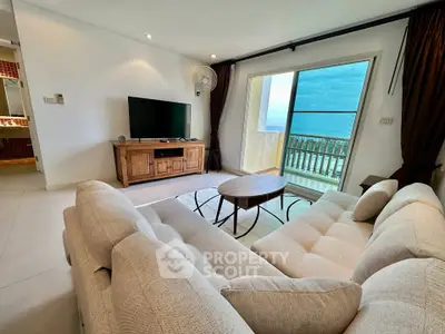 Spacious living room with modern furniture and balcony offering stunning ocean view.
