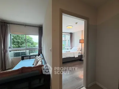Spacious apartment with cozy living room and bright bedroom, featuring large windows and modern decor.