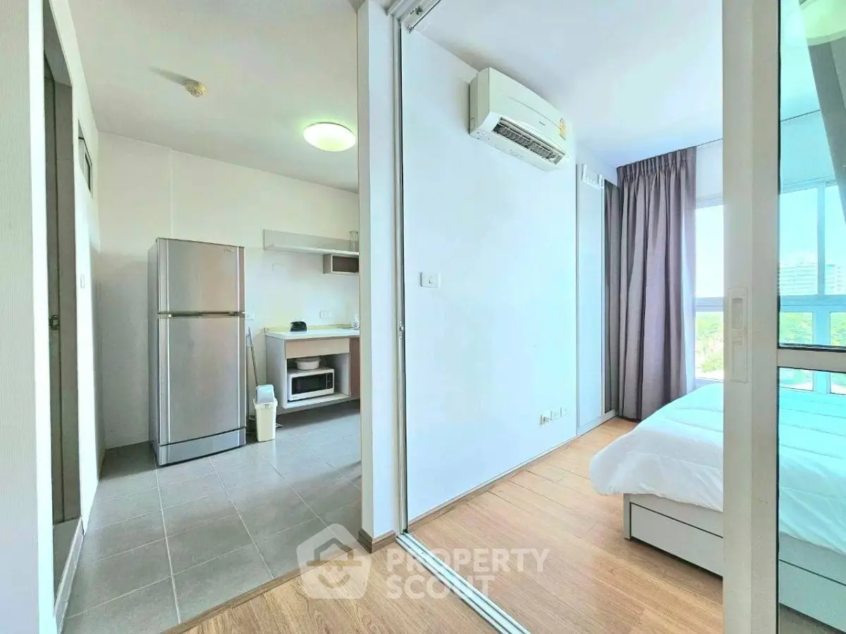 Modern apartment interior with kitchen and bedroom, featuring sleek appliances and natural light.