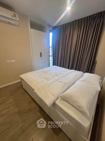 Cozy bedroom with modern design, featuring a comfortable bed, air conditioning, and ample natural light.