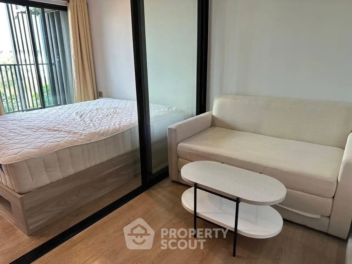 Modern studio apartment with cozy living area and bedroom separated by glass partition.