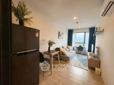 Modern living room with cozy seating and stylish decor, featuring a sleek black refrigerator and air conditioning.