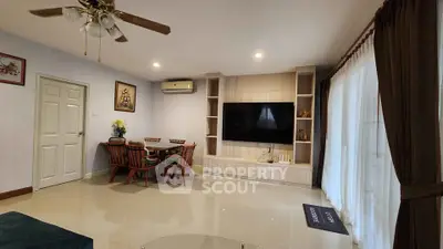 Spacious living room with modern decor and large TV, perfect for family gatherings.