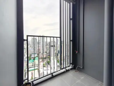 Modern high-rise balcony with cityscape view, sleek railing, and tiled flooring.