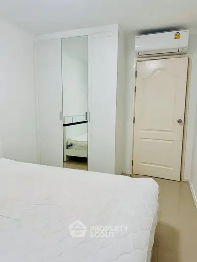 Cozy bedroom with mirrored wardrobe and air conditioning in modern apartment.