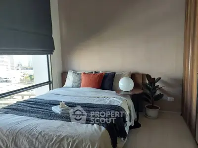 Cozy bedroom with modern decor and city view from large window.
