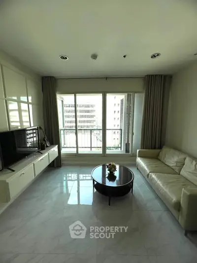 Spacious living room with modern decor and city view, featuring a comfortable sofa and sleek TV unit.
