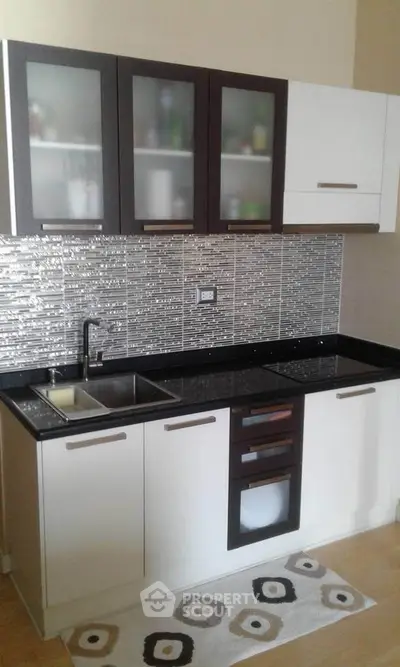 Modern kitchen with sleek cabinetry and stylish backsplash in a contemporary apartment.