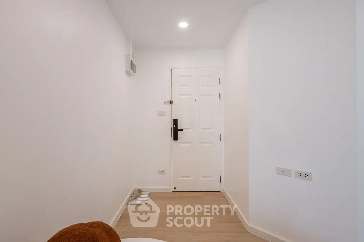 Minimalist apartment entrance with white door and wooden flooring