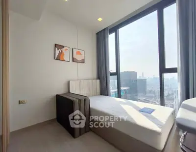 Modern bedroom with large window offering stunning city view, featuring minimalist decor and natural light.
