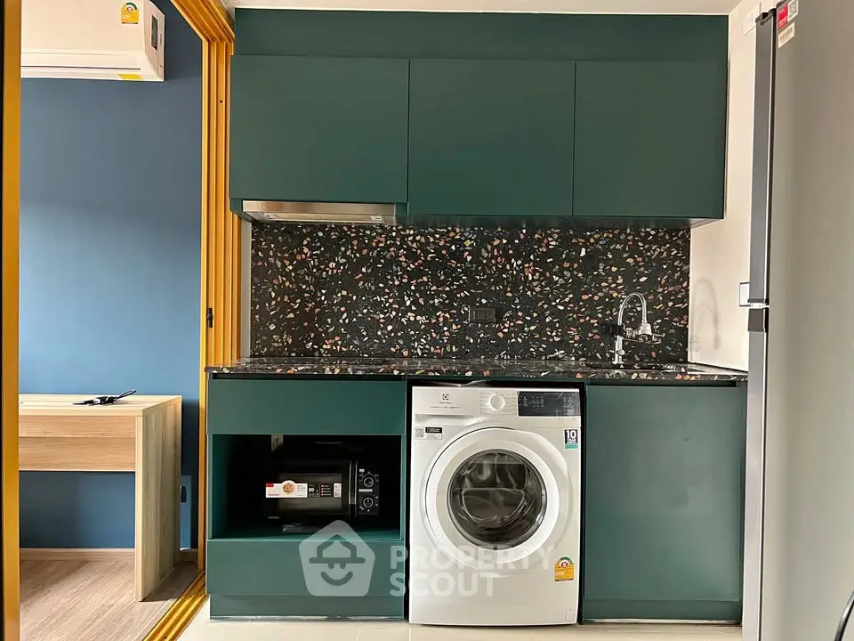 Modern kitchen with washing machine and stylish backsplash in compact apartment.